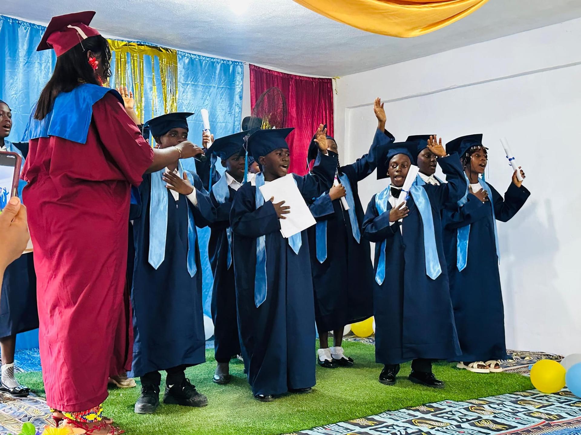 Des élèves diplômés chantant ensemble, les mains levées, pendant la cérémonie