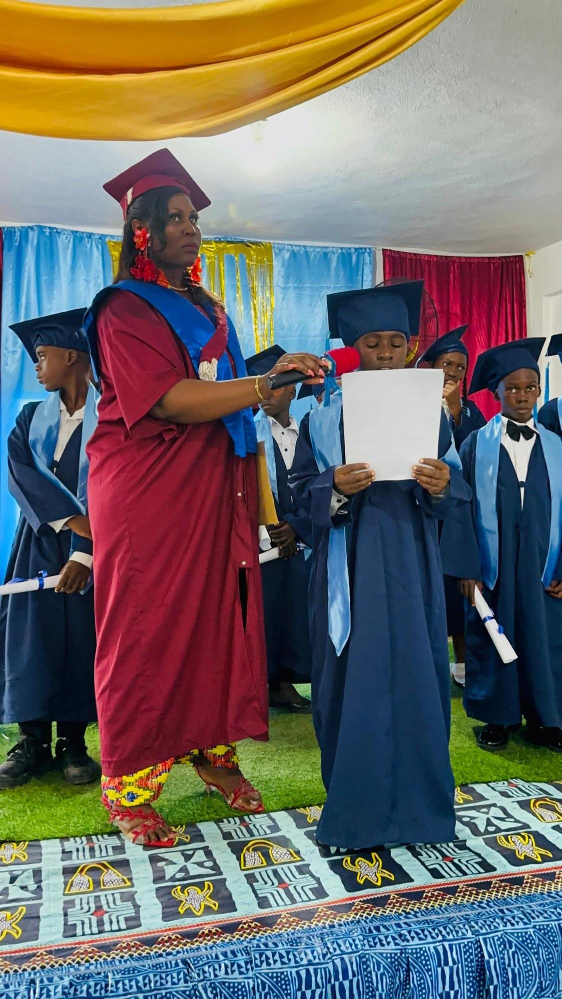 Un membre du personnel tenant le microphone pour un élève diplômé lisant un discours